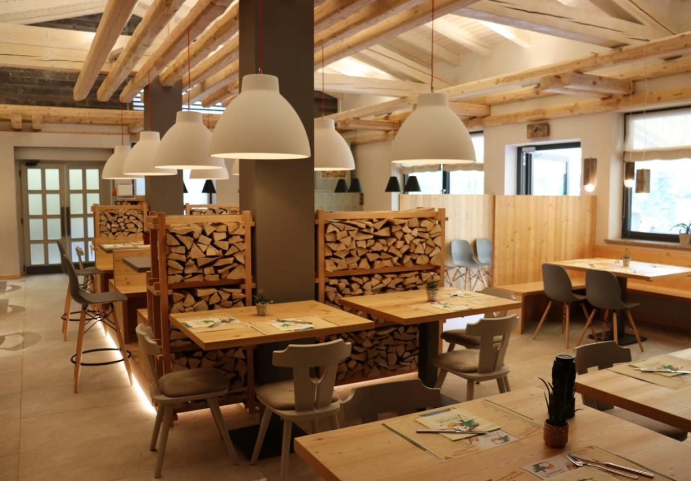 Ristorante moderno con arredi in legno, illuminazione elegante e atmosfera accogliente.