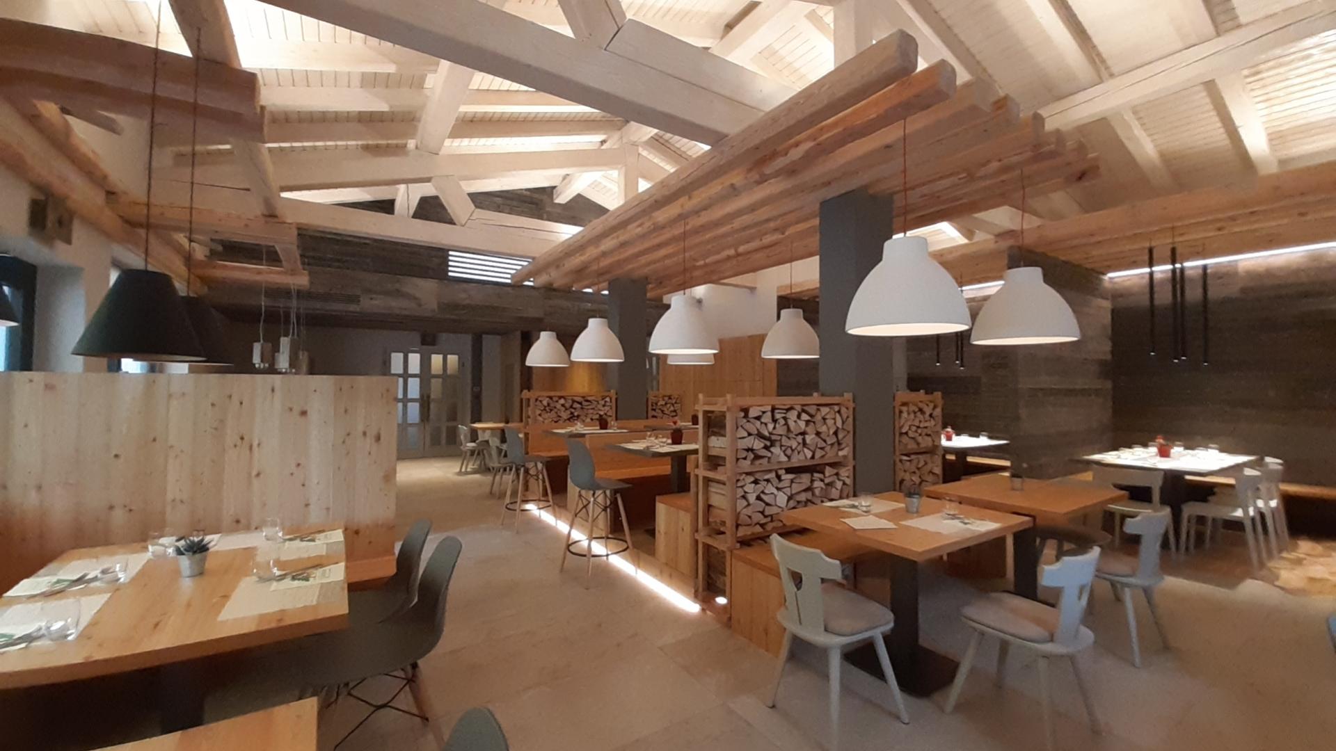 Ristorante moderno con interni in legno, illuminazione soffusa e tavoli apparecchiati elegantemente.