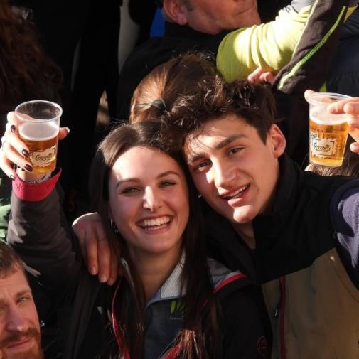 Giovani sorridenti brindano con bicchieri di birra in un momento di festa.