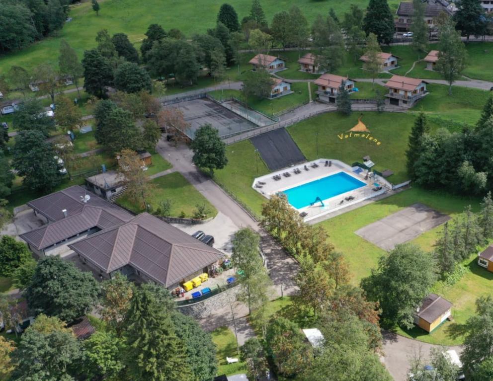 Villaggio turistico con piscina, bungalow e aree verdi immerse nella natura.